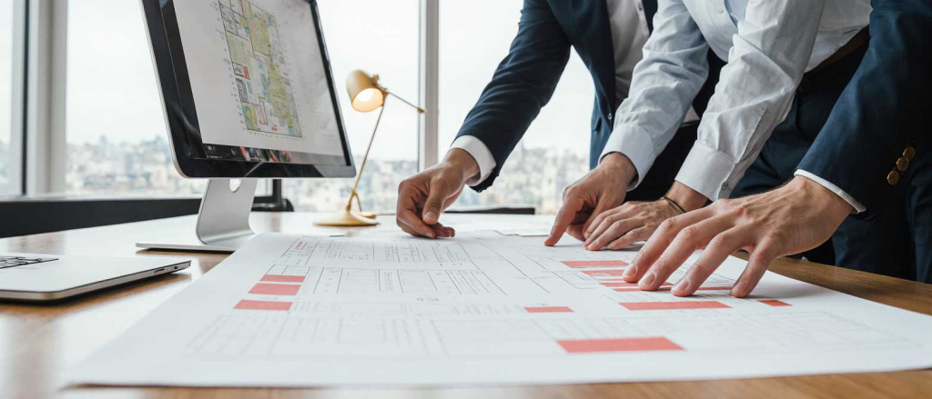 two_architects_discussing_floor_plans_spread_on_drafting_table_professionals_in_smart_casual_attire_6kowx84cevkiuwmd1hs4_2.jpg